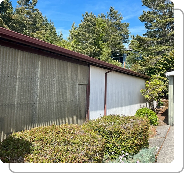 A building with a fence and bushes in front of it.