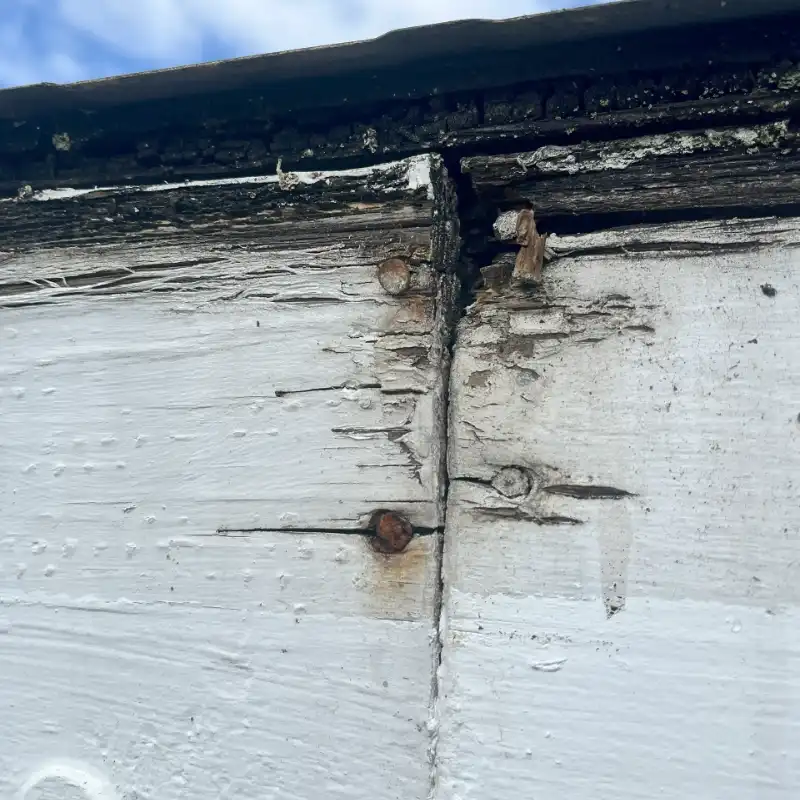 A close up of the side of a building with peeling paint.