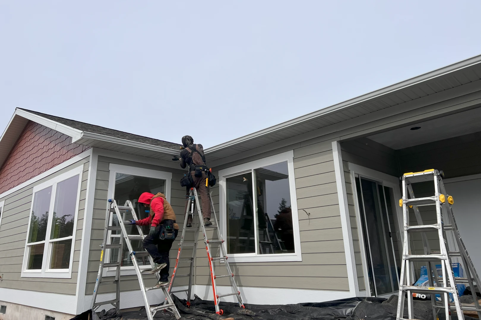 A man on a ladder and another man in the window.