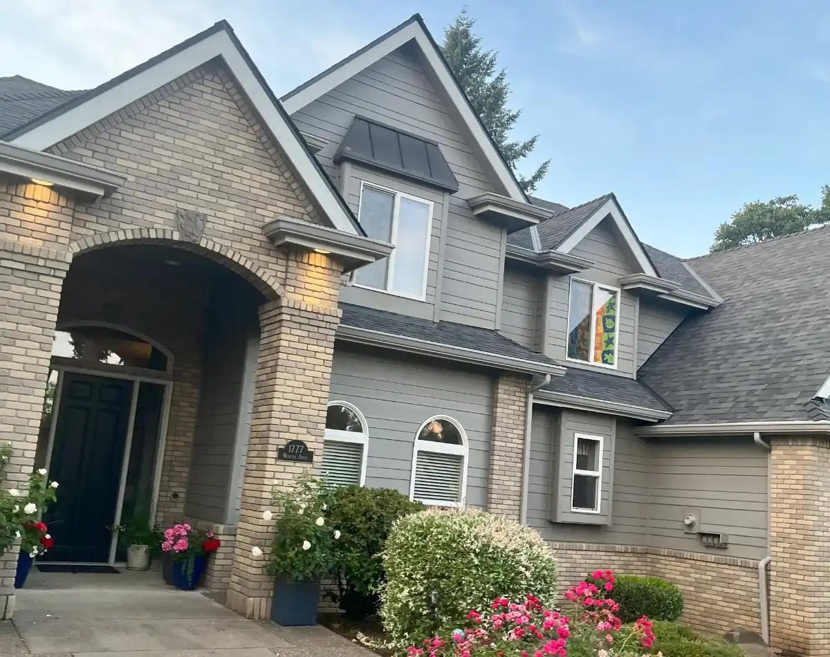 Brick house with a black door and flowers.